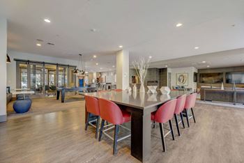 `A modern kitchen with a long island and red chairs.